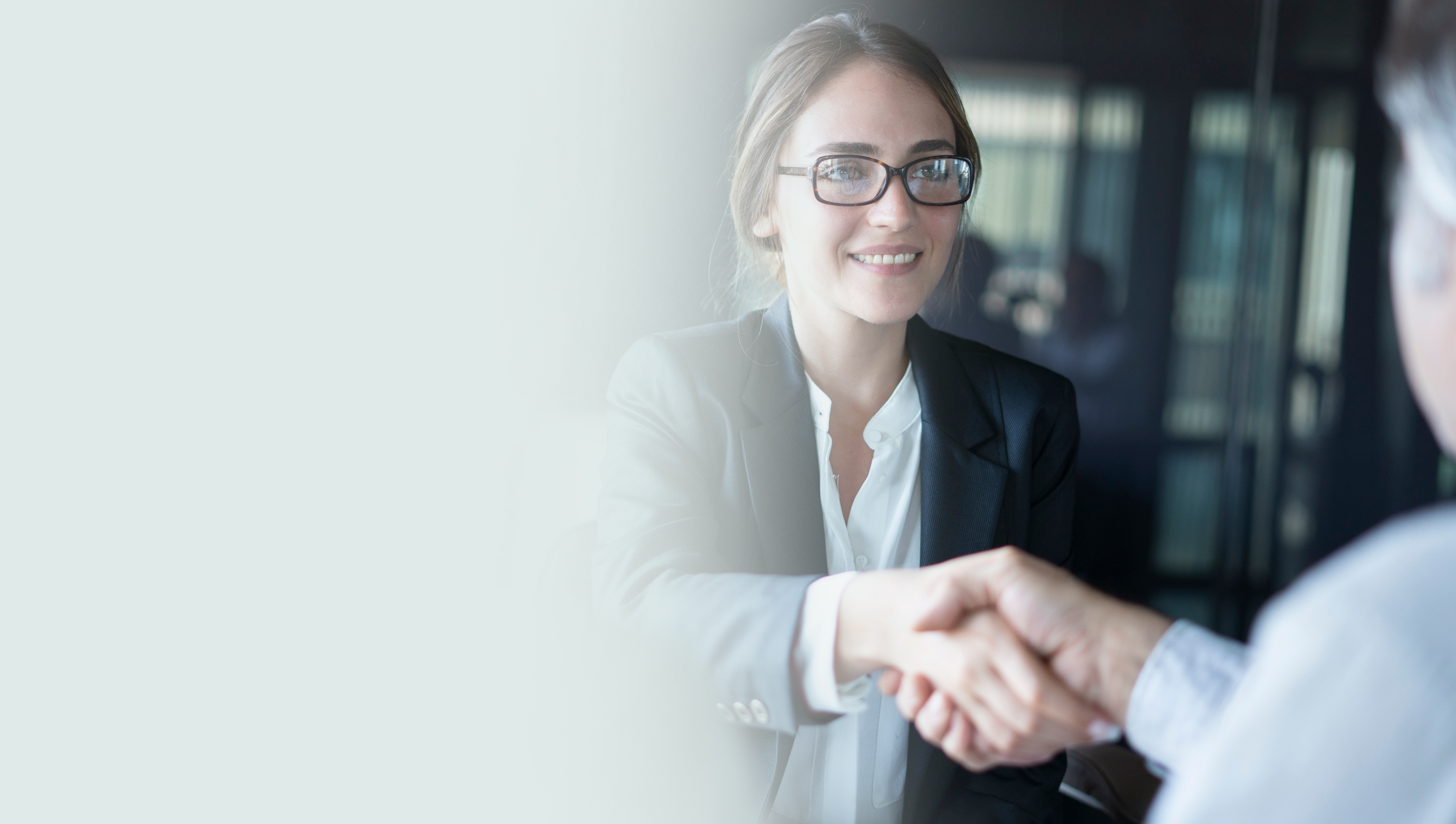 Woman and man shaking hands at desk during business meeting. 